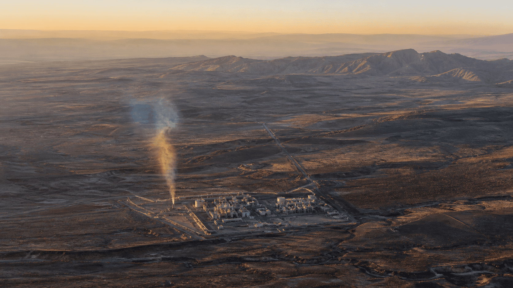 An aerial view of industrial terrain with a subtle spectral methane plume rising from one source